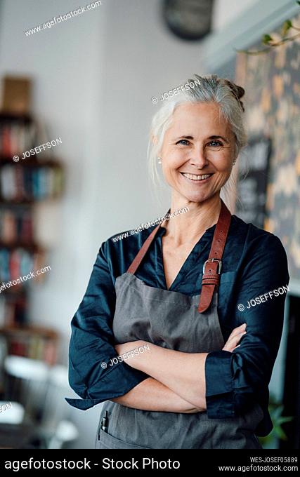 Female entrepreneur standing with arms crossed in cafe