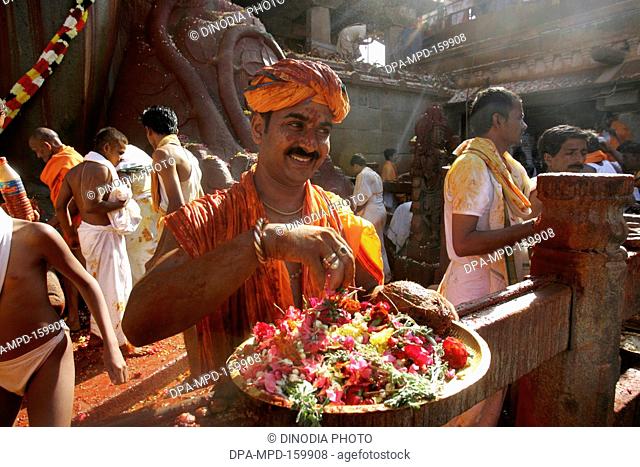 Devotee carrying plate full of flowers to sprinkle on 18 meter high statue of Bhagwan Gomateshwara Bahubali during Mahamasthakabhisheka Jain festival held once...