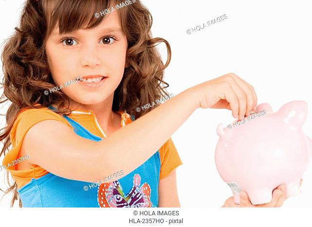 Portrait of a girl putting a coin into a piggy bank