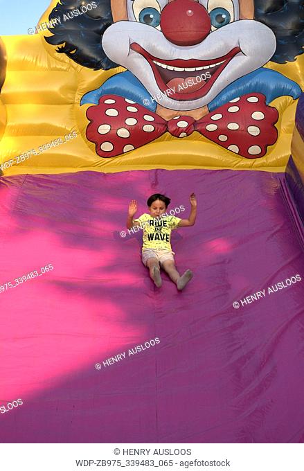 Young boy plays on a big slider, scared