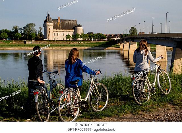 YOUNG WOMEN CYCLING ALONG THE 'LOIRE A VELO' CYCLING ITINERARY IN FRONT OF THE CHATEAU OF SULLY-SUR-LOIRE, SAINT-PERE-SUR-LOIRE, LOIRET 45, FRANCE