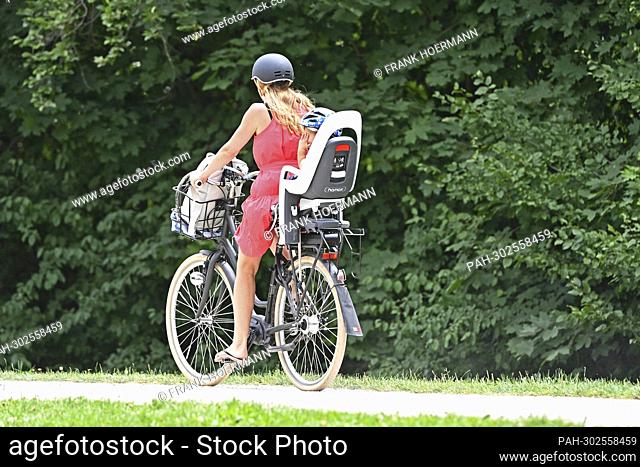 Woman rides on her bike in a child seat sits a toddler. - Munich/Bayern/Deutschland