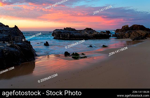 Seaside tranquility, calm ocean with gentle waves wash onto shore through ooastal rocks and beautiful sky full of colours overhead with reflections in the wet...