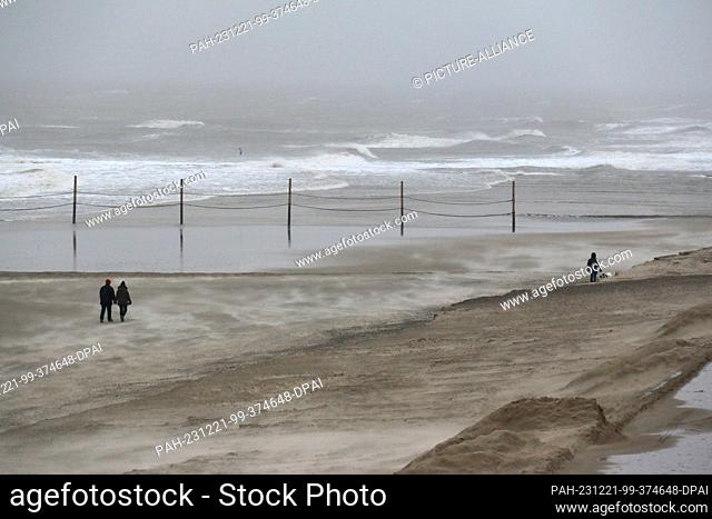 21 December 2023, Lower Saxony, Wangerooge: Beach walkers brave the wind on the island of Wangerooge. The German Weather Service in Offenbach warns of...