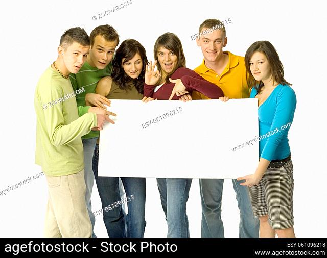 Group of 6 teenagers holding and pointing white blank board. They're looking at camera. White background behind them