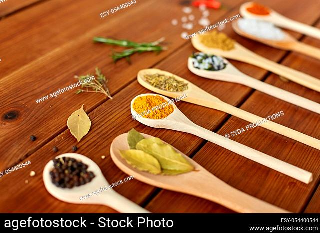 spoons with spices and salt on wooden table