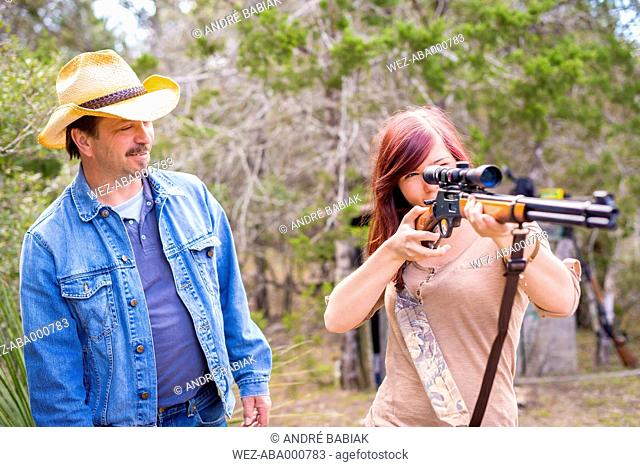 USA, Texas, Man guiding woman to hunting rifle