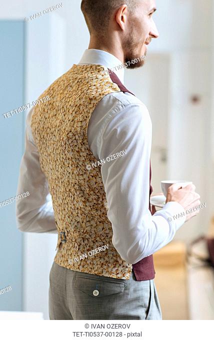 Man wearing patterned waistcoat holding tea cup