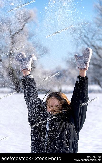 A girl throws snow into the air