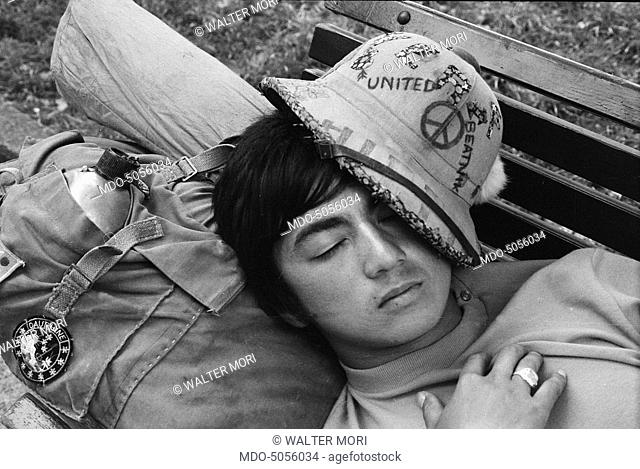 Asian tourist sleeping on a bench on August 15th in Milan. Milan, 15th August 1968