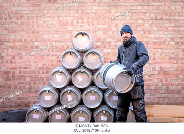 Portrait of brewer by stack of barrels in small brewery