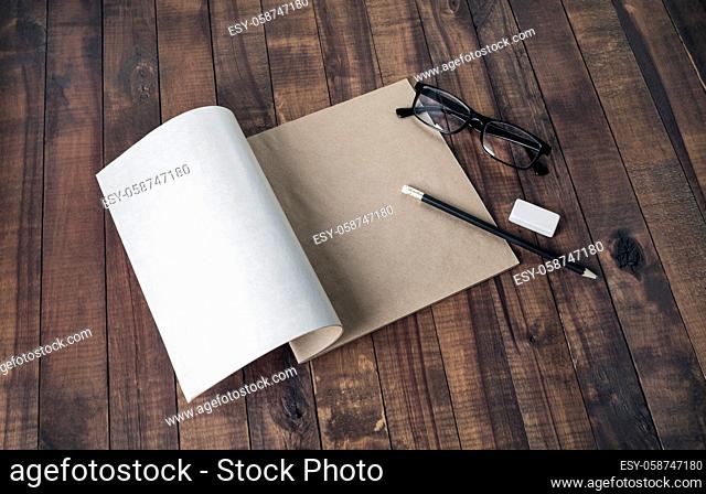Blank brochure, glasses, pencil and eraser, on wooden table background. Responsive design mockup