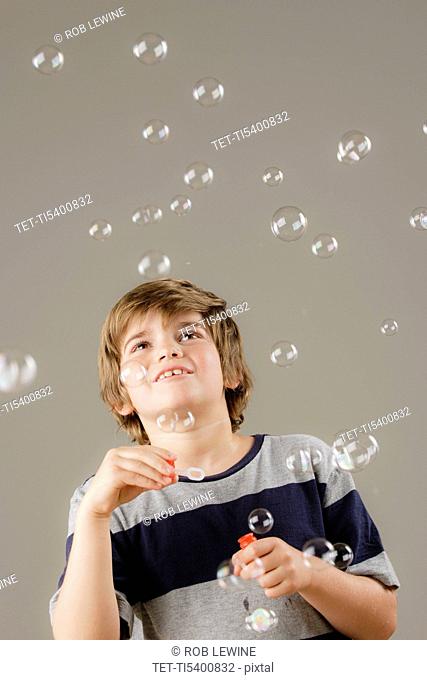 Studio shot of boy 8-9 blowing bubbles