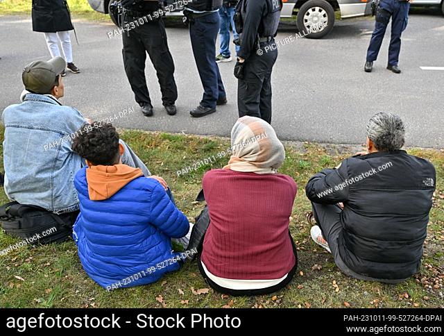 11 October 2023, Brandenburg, Roggosen: Illegal migrants, here a family, sit in front of Federal Police officers after being apprehended near Forst (Lausitz)