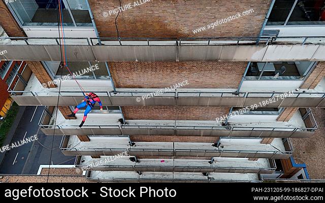05 December 2023, North Rhine-Westphalia, Mönchengladbach: A height rescuer from the Mönchengladbach fire department dressed as Spiderman abseils down from the...