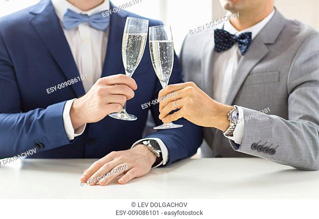 people, celebration, homosexuality, same-sex marriage and love concept - close up of happy married male gay couple in suits and bow-ties drinking sparkling wine...