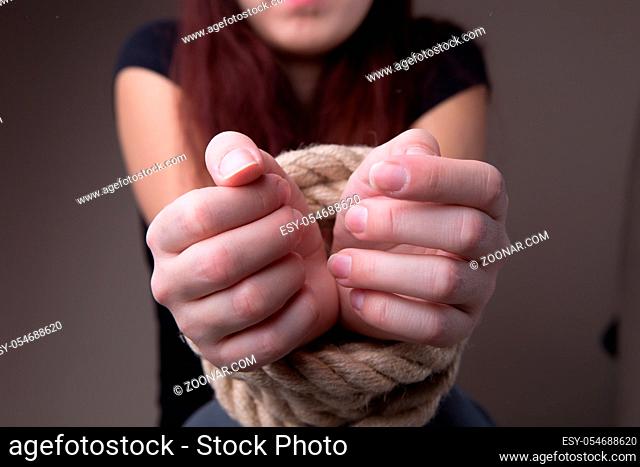 Girl victim with rope tied hands at blank background