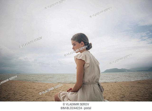 Caucasian women wearing dress sitting on beach