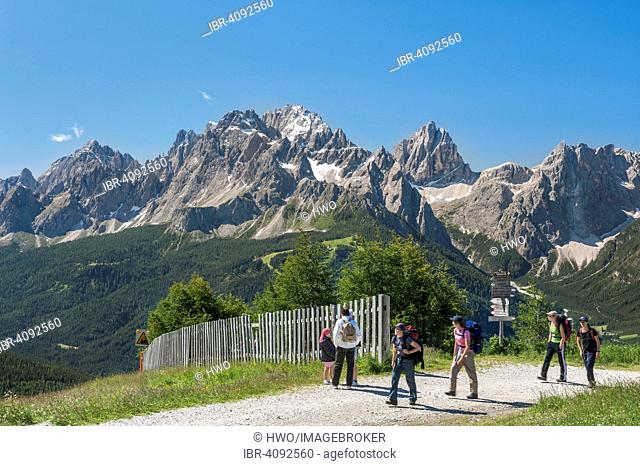 Hikers on Mt Helm, Sexten Dolomites with the mountains Croda Rossa or Sextener Rotwand, Elfer and Zwölfer, and Monte Elmo, South Tyrol, Italy