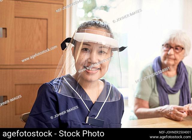 Smiling home carer wearing face shield