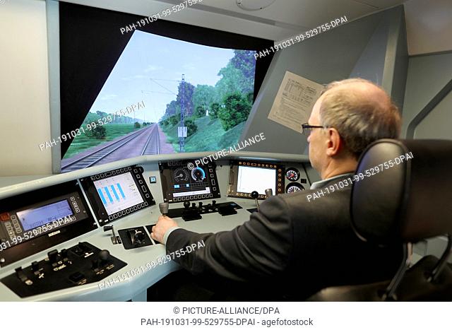 31 October 2019, North Rhine-Westphalia, Cologne: An employee of the railway trains in a driving simulator. Deutsche Bahn (DB) has opened a new training centre...