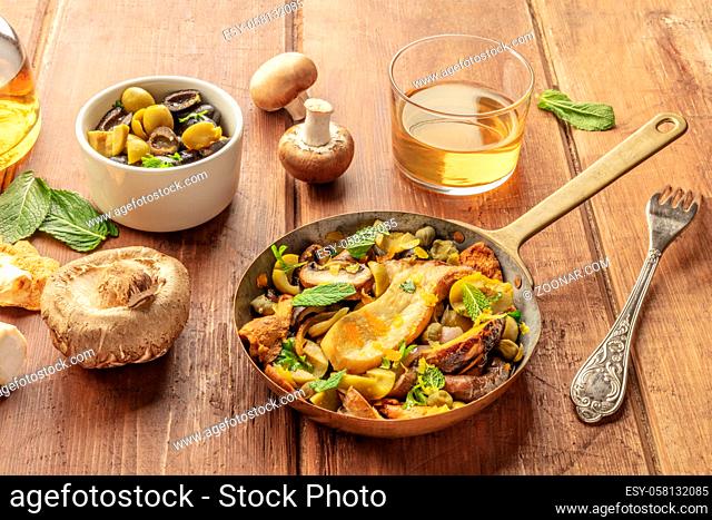 A rustic mushrooms and olives saute with mint and a glass of white wine