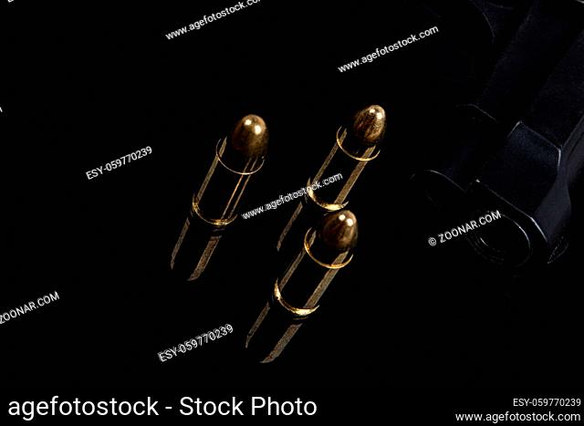 Gold bullets and gun on black background