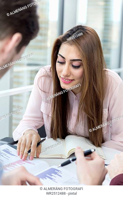 Smiling businesswoman analyzing graph with male colleague in meeting