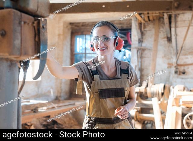 Woman carpenter in traditional carpentry adjusting the machine planer by hand