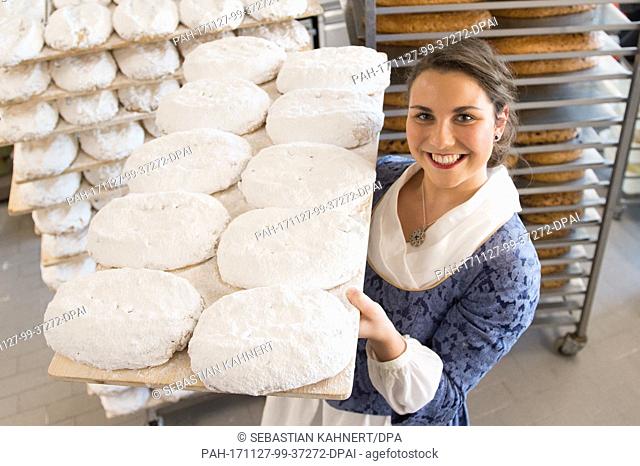 The 23rd Dreden Stollenmaedchen (lit. stollen bread girl) Hanna Haubold holds a board with stollen in the bakery Wippler inÂ Dresden, Germany, 27 November 2017