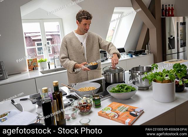 05 October 2023, Bavaria, Munich: National soccer player Thomas Müller stands at a stove during the presentation of the cookbook ""Kochen für kleine & große...