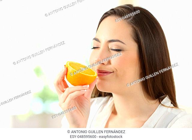 Portrait of a pretty woman smelling half orange at home