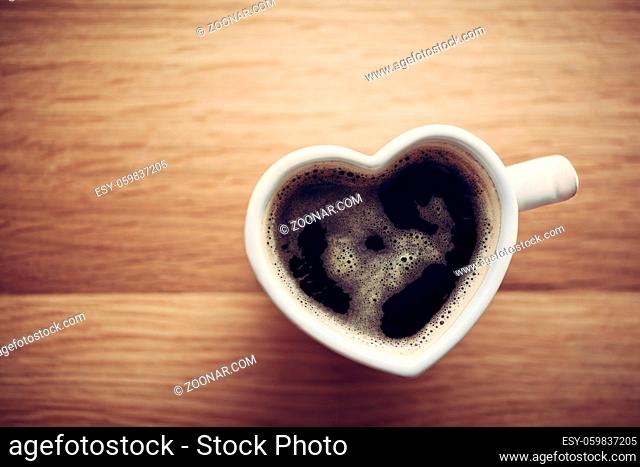 Black coffee, espresso in heart shaped cup. Love concept, Valentine#39;s Day. View from the top, vintage