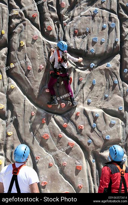 girl climbs a big rock wall at the gym
