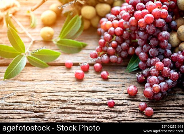 Fresh mixed fruits on wood table background, Red grape, Longkong, Langsat. With sun light in the morning