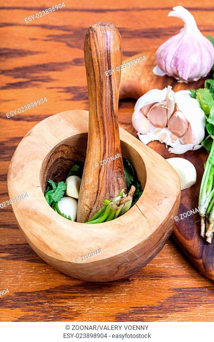 wood mortar with cilantro herb and garlic on table