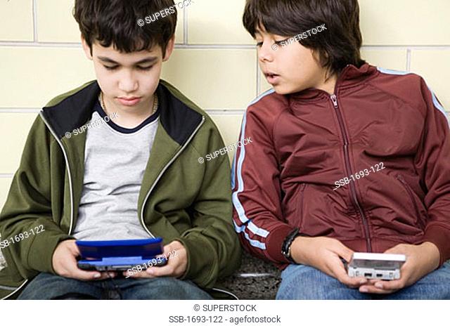 Two boys playing with handheld video games