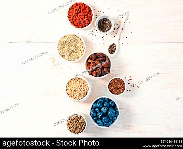 Various superfoods in small bowl on white wooden table.Selection super food.Superfood as blueberry, chia, raw cocoa bean, goji, hemp seeds, quinoa, brown rice