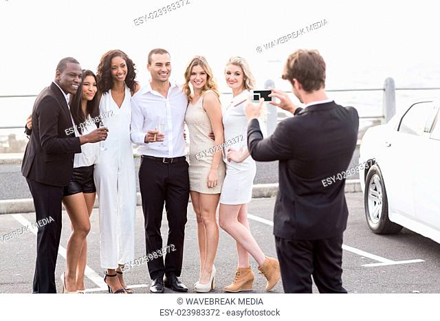 Well dressed people taking pictures next to a limousine