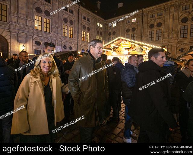 19 December 2023, Bavaria, Munich: Markus Söder (CSU, center l), Minister President of Bavaria, strolls through the Christmas market in the ""Kaiserhof"" of the...