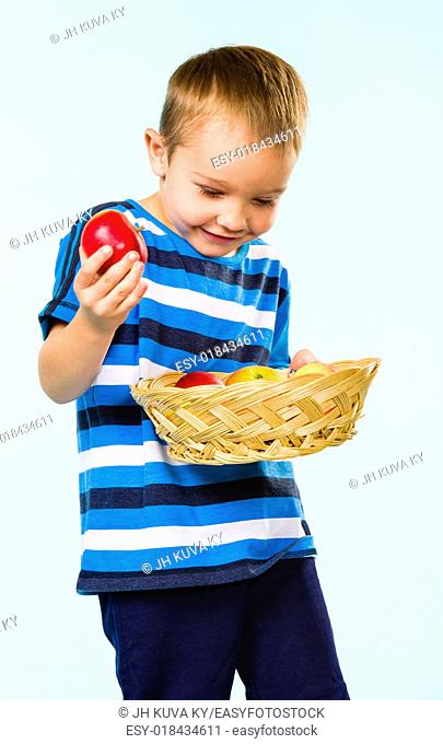 Little boy on striped t-shirt, fruit basket, studio shot and light blue background