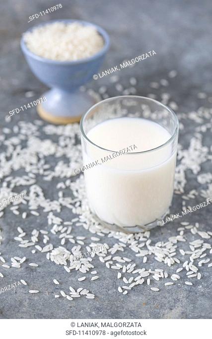 A glass of rice milk surrounded by grains of rice