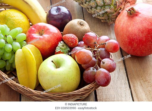 Wicker basket filled with fresh fruits against wooden background