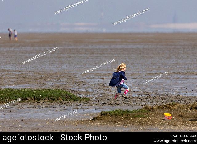 Harlesiel / Carolinensiel, Germany June 2020: Symbolic pictures - 2020 A little girl runs through the Wadden Sea in front of Harlesiel at low tide