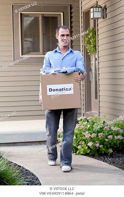 USA, Illinois, Metamora, Man carrying cardboard box in front of house