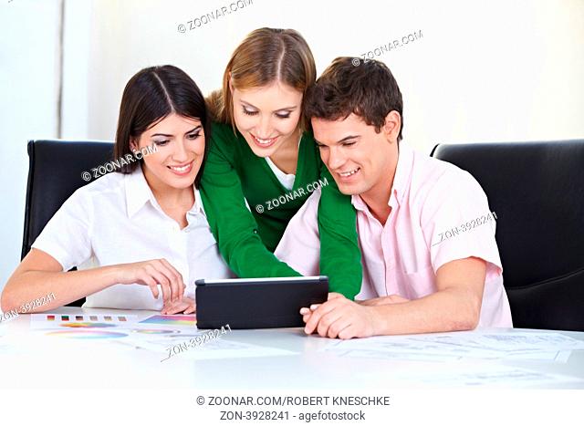 Drei Studenten am Schreibtisch lernen gemeinsam am Tablet PC