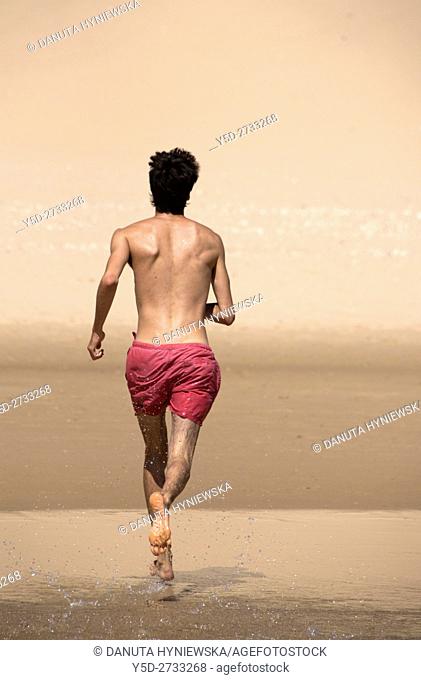 young man running on the beach, vacation time, here Salema beach, Algarve, Portugal, Europe