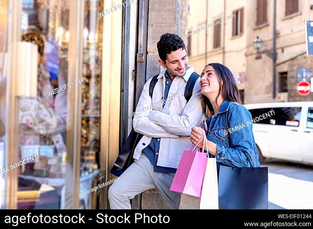 Smiling male tourist looking at woman while standing by store window