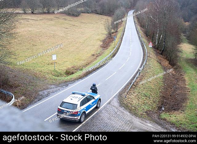31 January 2022, Rhineland-Palatinate, Mayweilerhof: Police officers stand at a barricade on county road 22, about a kilometer from the scene where two police...