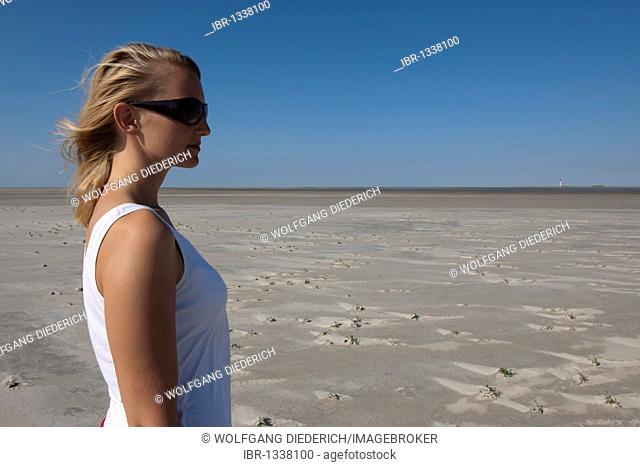 Young woman, 20-25 years, looking in the distance on a sunny summer day on the beach of St Peter Ording, North Sea, North Friesland, Schleswig-Holstein